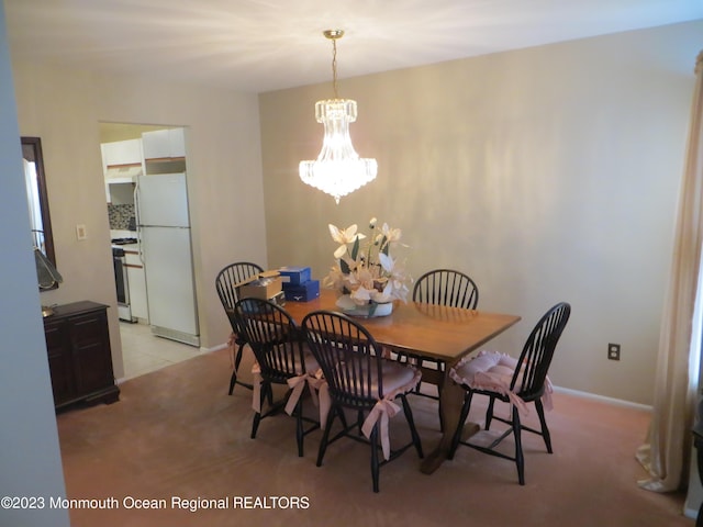 dining area with light colored carpet, a notable chandelier, baseboards, and light tile patterned flooring