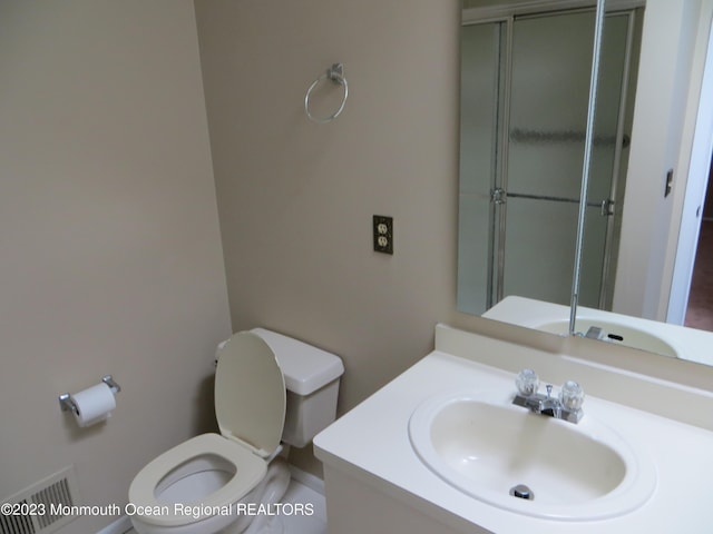 bathroom featuring toilet, a shower with door, visible vents, and vanity