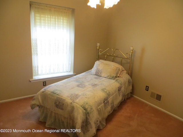 carpeted bedroom with visible vents, baseboards, and an inviting chandelier