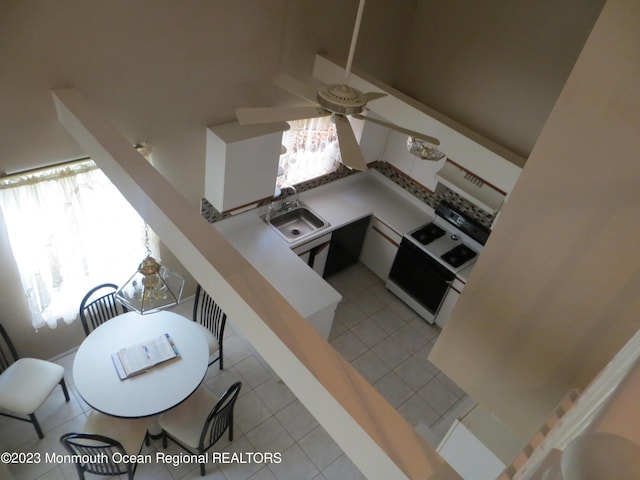 kitchen with light tile patterned floors, electric range oven, and a sink