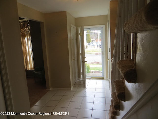 doorway with baseboards and light tile patterned floors