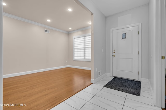 foyer entrance with light hardwood / wood-style floors and crown molding