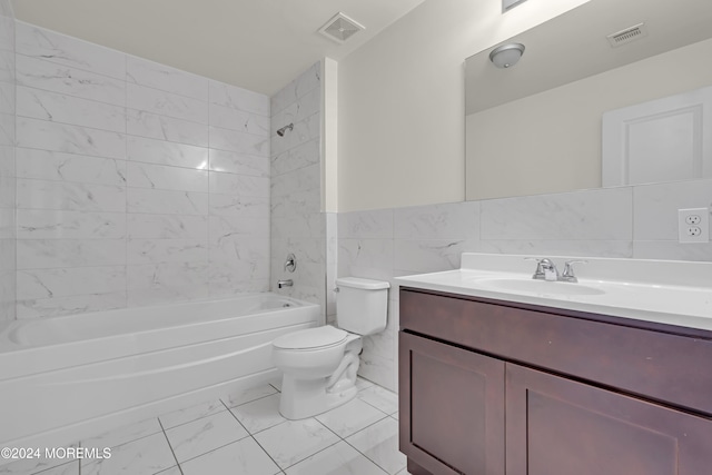 full bathroom with tiled shower / bath, vanity, toilet, and tile walls