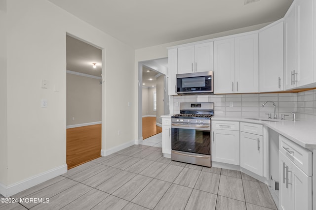 kitchen featuring crown molding, white cabinets, light hardwood / wood-style floors, and appliances with stainless steel finishes