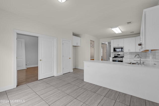 kitchen featuring white cabinets, sink, appliances with stainless steel finishes, tasteful backsplash, and kitchen peninsula