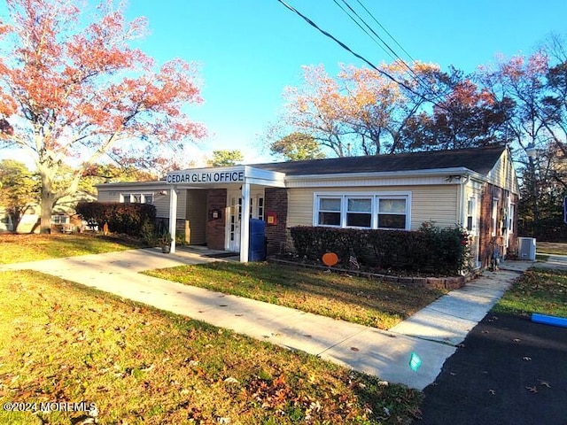 view of front of house featuring a front yard, brick siding, and central AC unit