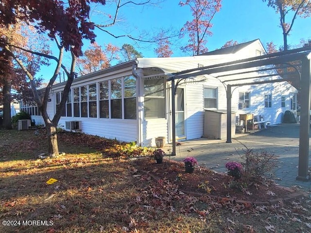 view of home's exterior with a sunroom and cooling unit