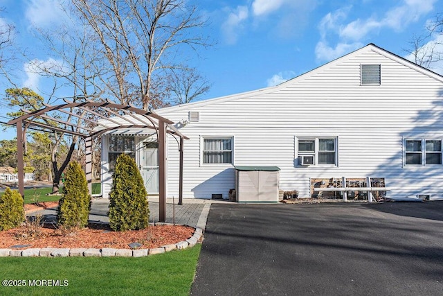 view of property exterior with cooling unit and a pergola