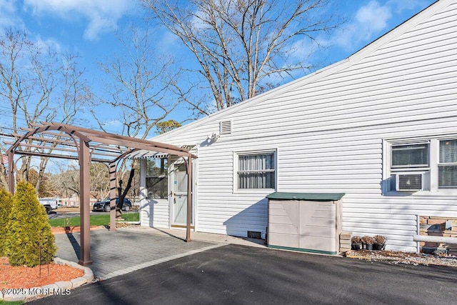 view of property exterior with cooling unit and a pergola