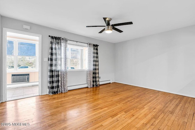 empty room featuring ceiling fan, an AC wall unit, a baseboard heating unit, and light wood-style flooring