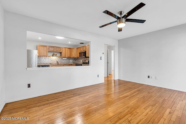 unfurnished living room featuring light wood-style flooring, baseboards, and a ceiling fan