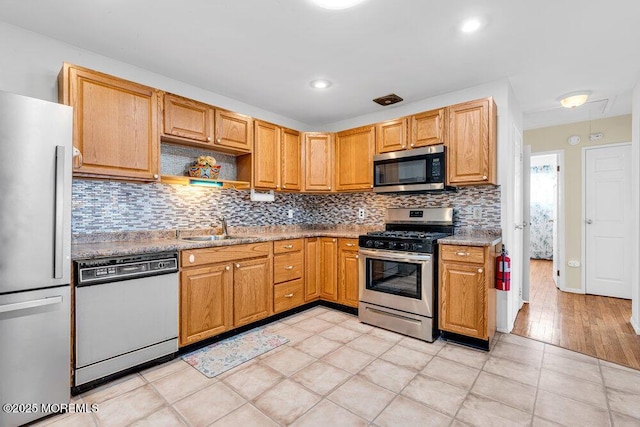 kitchen with light tile patterned floors, stainless steel appliances, open shelves, decorative backsplash, and a sink