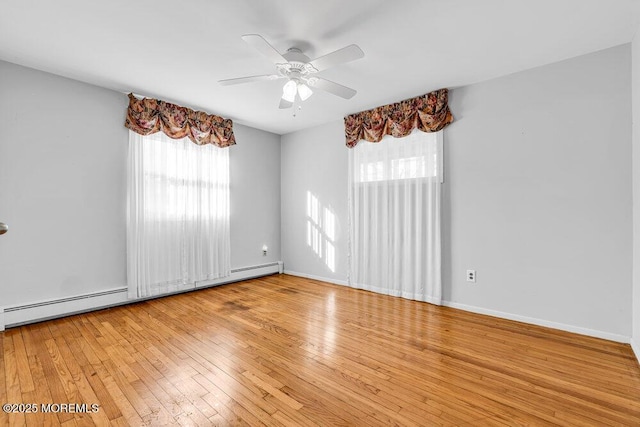 spare room with a baseboard heating unit, ceiling fan, hardwood / wood-style flooring, and baseboards