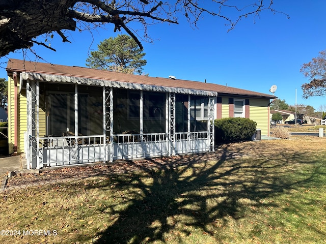 back of house featuring a yard and a sunroom