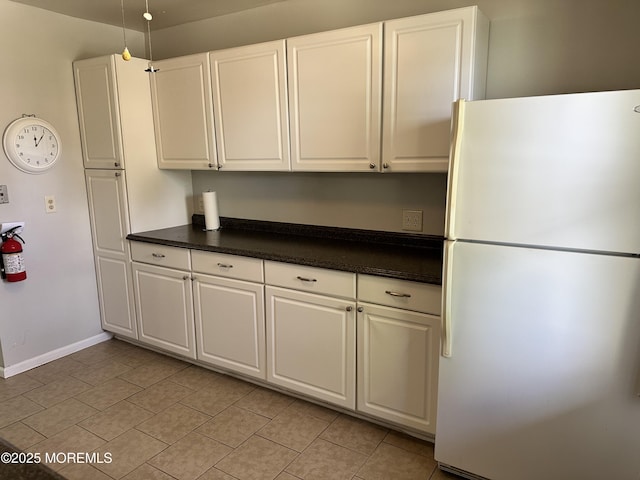 69 Chelsea Dr Unit 72, Manchester, NJ 08759 - kitchen featuring freestanding refrigerator, dark countertops, white cabinetry, light tile patterned floors, and baseboards