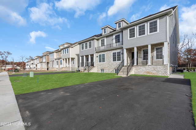 view of front of property with a front yard, a porch, and a balcony