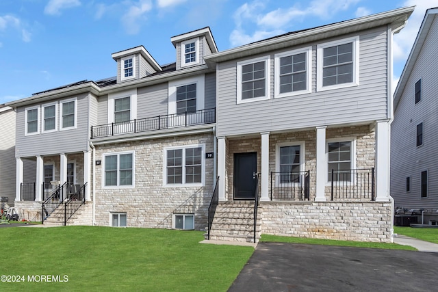 view of front of home featuring a front yard, a balcony, and covered porch