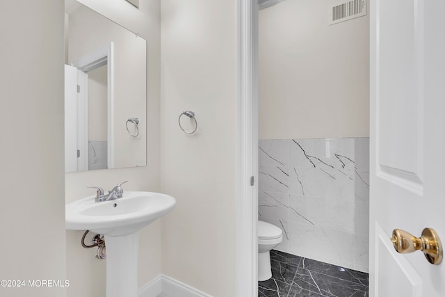 bathroom featuring sink, toilet, and tile walls