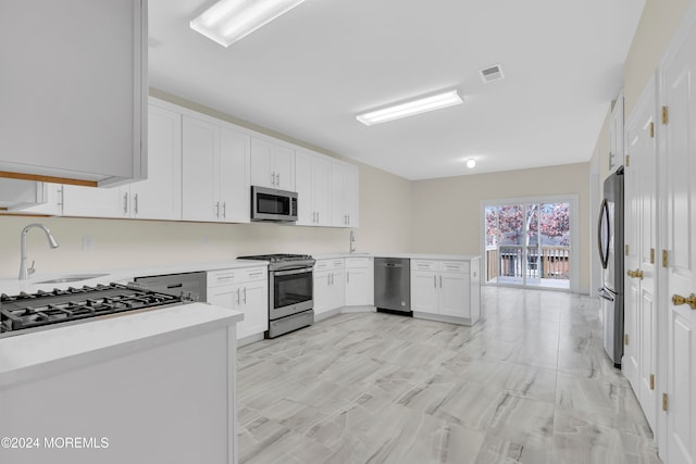 kitchen featuring kitchen peninsula, white cabinetry, sink, and appliances with stainless steel finishes