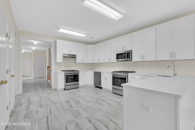 kitchen with white cabinets, stainless steel appliances, kitchen peninsula, and sink