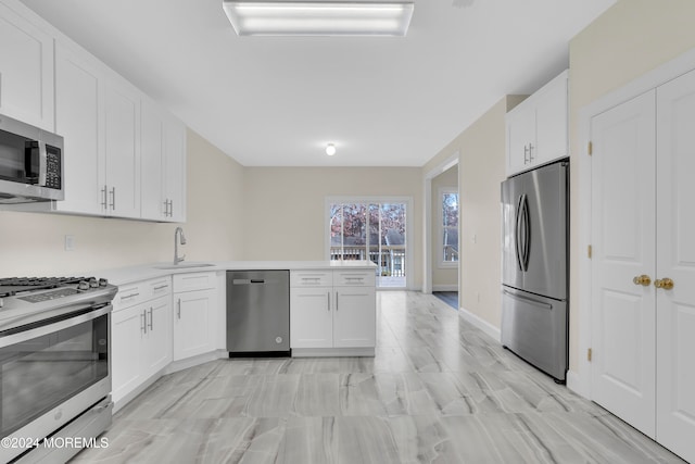 kitchen featuring kitchen peninsula, sink, white cabinets, and appliances with stainless steel finishes