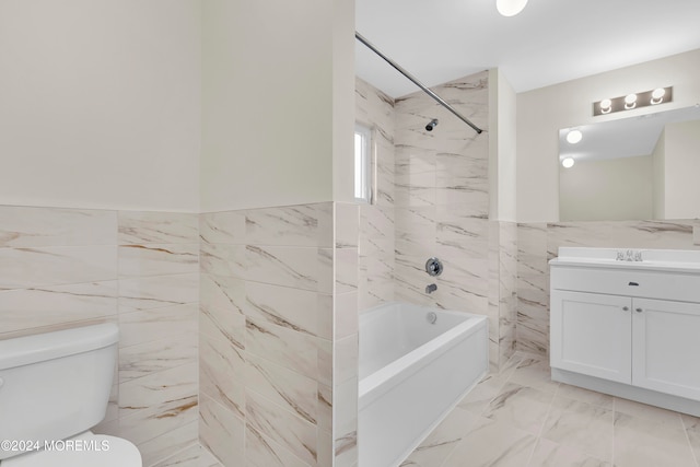 full bathroom with vanity, tiled shower / bath combo, toilet, and tile walls