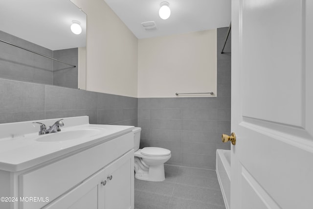 full bathroom featuring vanity, tile patterned floors, washtub / shower combination, toilet, and tile walls