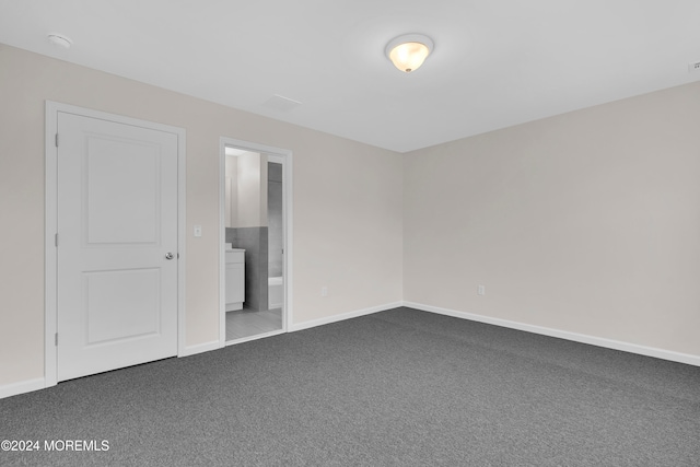 unfurnished bedroom with connected bathroom and carpet floors