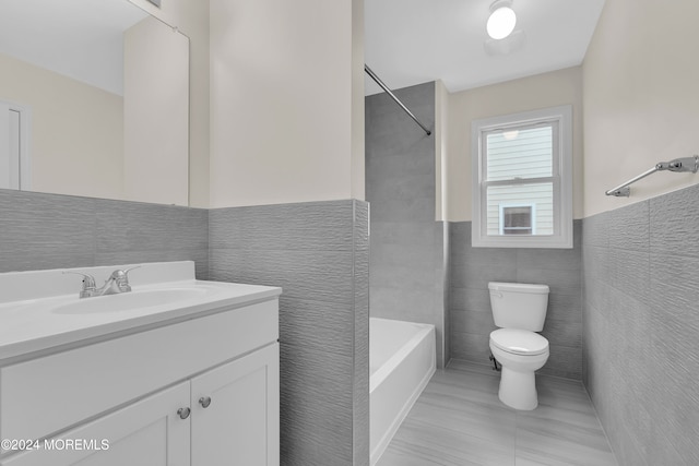 full bathroom with tile patterned floors, vanity, tile walls, and toilet