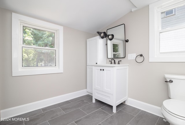 bathroom with vanity, vaulted ceiling, toilet, and tile patterned flooring