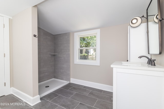 bathroom featuring tiled shower, tile patterned floors, vanity, and vaulted ceiling