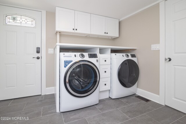 laundry area with cabinets, dark tile patterned floors, and washing machine and clothes dryer