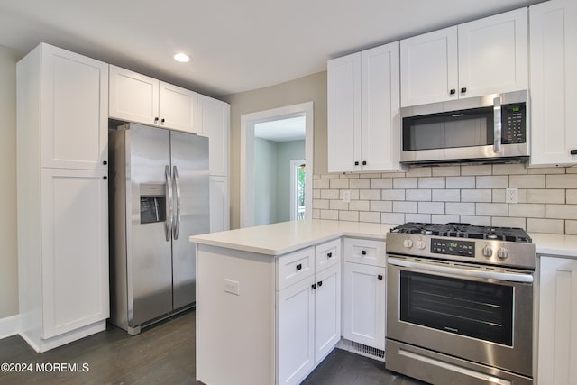 kitchen with kitchen peninsula, dark hardwood / wood-style flooring, white cabinets, and appliances with stainless steel finishes