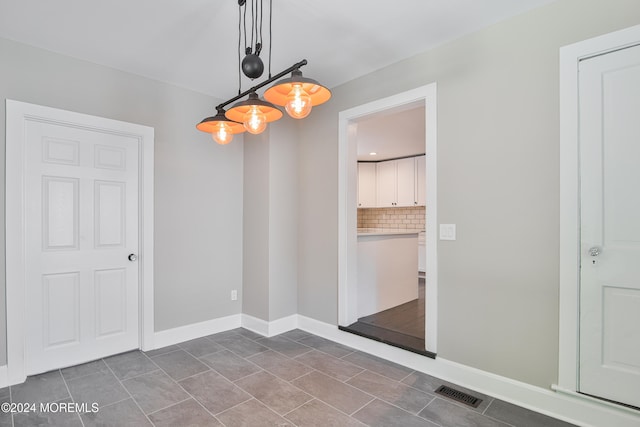 unfurnished dining area with dark tile patterned flooring