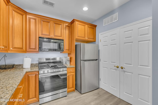 kitchen with light stone countertops, stainless steel appliances, and light hardwood / wood-style floors