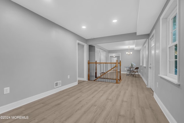 spare room with light hardwood / wood-style flooring and an inviting chandelier