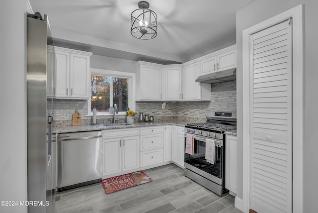 kitchen with backsplash, white cabinets, sink, light stone countertops, and stainless steel appliances