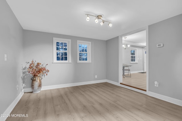 empty room with light hardwood / wood-style floors and an inviting chandelier