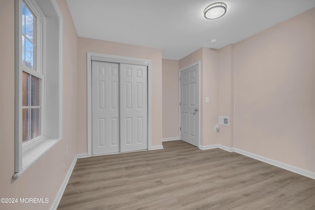 unfurnished bedroom featuring light hardwood / wood-style flooring and a closet