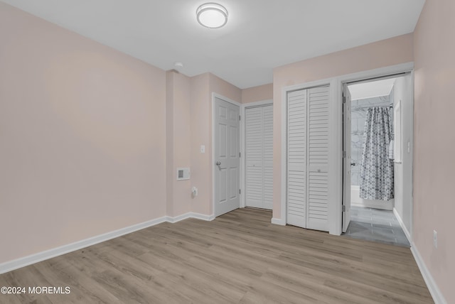 unfurnished bedroom with connected bathroom and light hardwood / wood-style floors