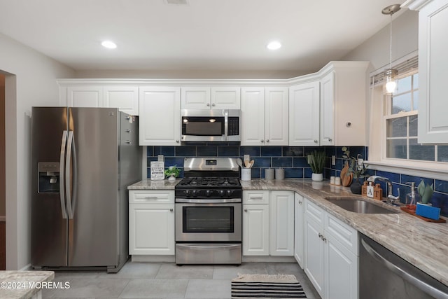 kitchen featuring appliances with stainless steel finishes, backsplash, sink, decorative light fixtures, and white cabinetry