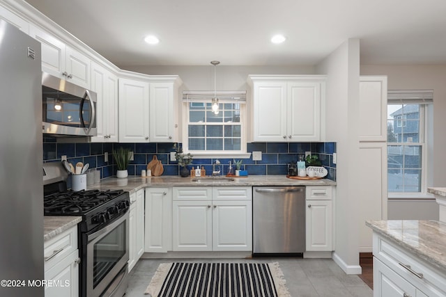 kitchen with white cabinets, decorative backsplash, pendant lighting, and appliances with stainless steel finishes