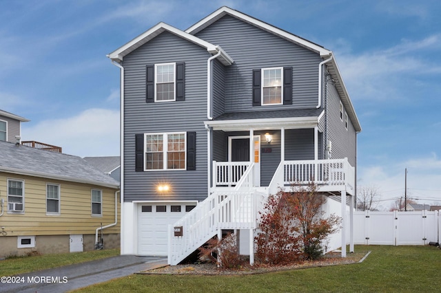 view of property with covered porch, a garage, and a front lawn