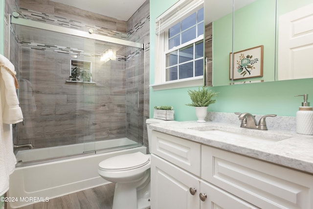 full bathroom featuring hardwood / wood-style flooring, vanity, toilet, and bath / shower combo with glass door