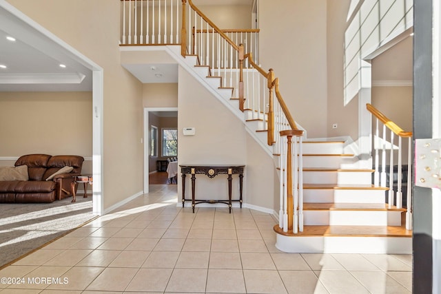 staircase featuring tile patterned flooring, ornamental molding, and a high ceiling