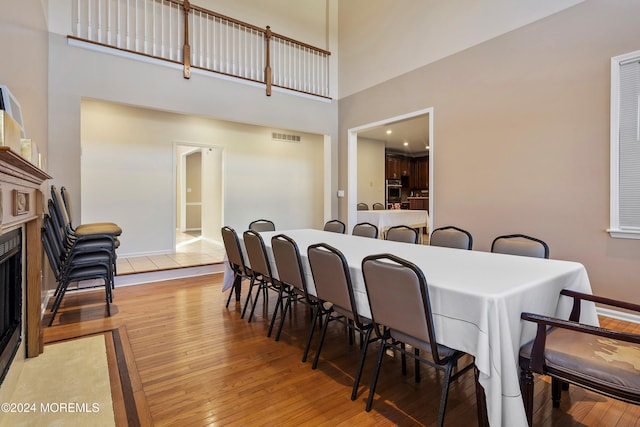 dining room featuring a towering ceiling and wood-type flooring