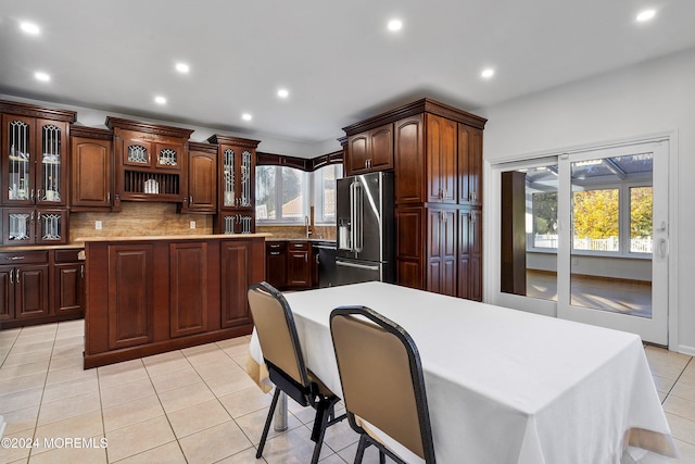 kitchen featuring dark brown cabinetry, a center island, light tile patterned flooring, and appliances with stainless steel finishes