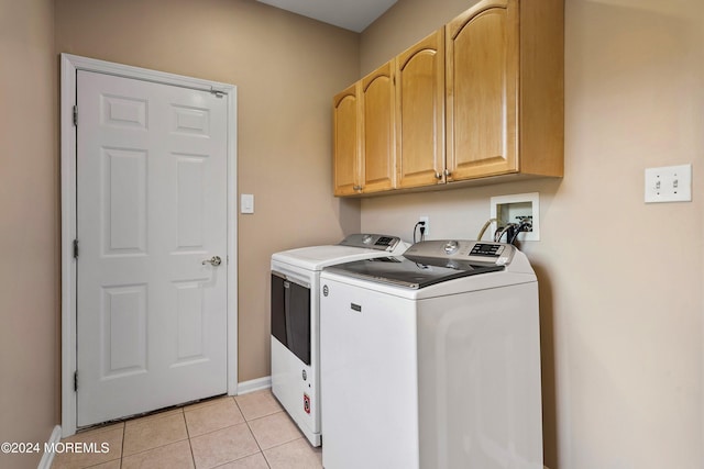 washroom featuring cabinets, light tile patterned floors, and washing machine and clothes dryer