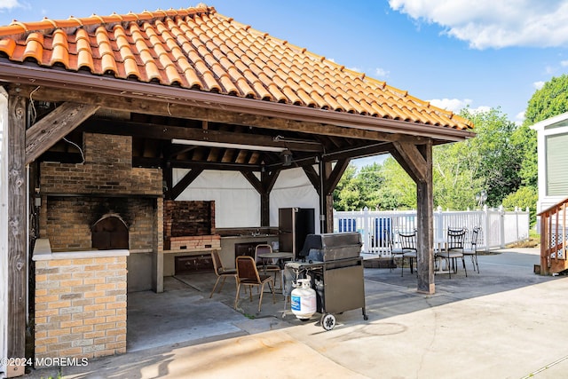 view of patio with a gazebo, area for grilling, a fireplace, and an outdoor kitchen