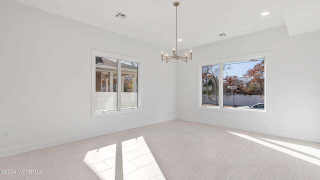 spare room featuring a healthy amount of sunlight and a notable chandelier